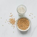 top view photo of soybeans on bowl near drinking glass with soy milk